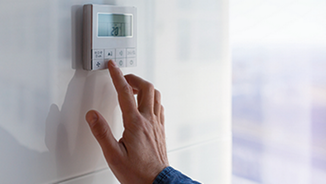 Hand auf Temperaturregler im Büro zum Thema Temperatur am Arbeitsplatz © AdobeStock_oneinchpunch