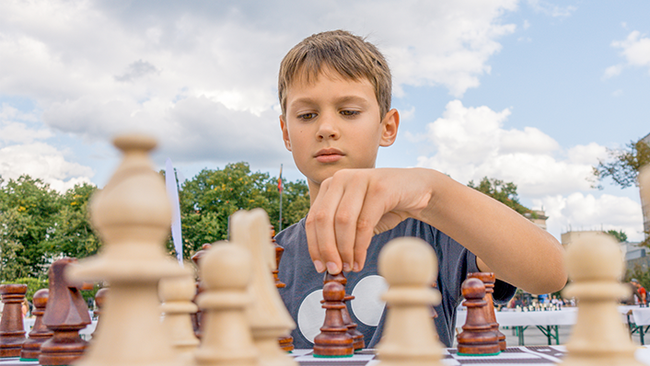 Kind beim Schachspielen am Stra&szlig;enfest &copy; vejaa - stock.adobe.com